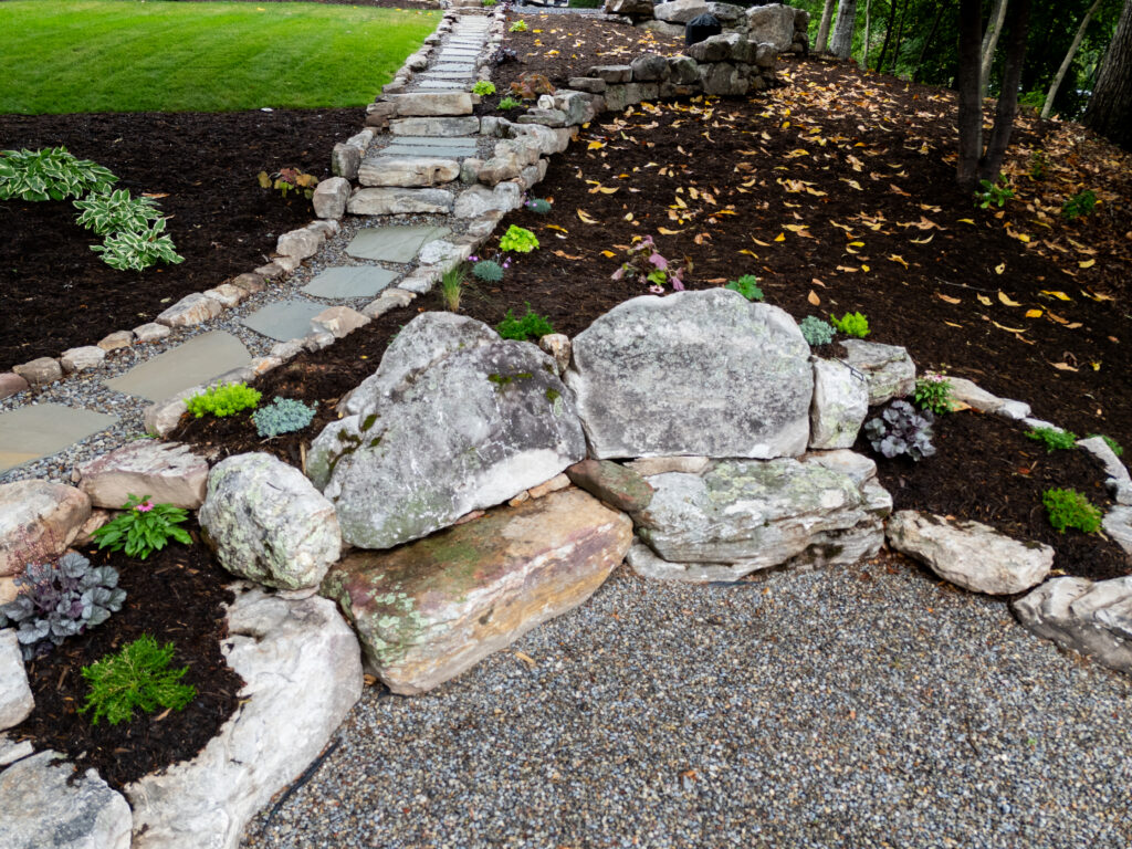 Natural stone boulder wall with seating by Precision Landscaping & Design